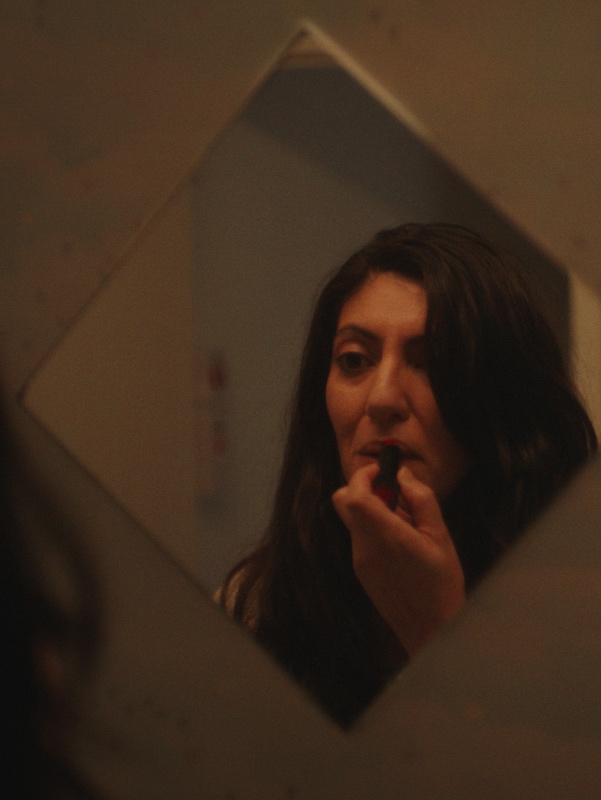Leyla applies lipstick in mirror